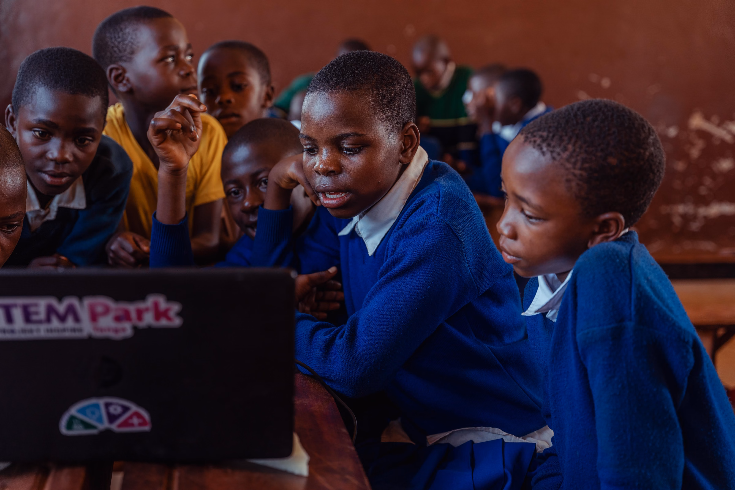 Primary school learners gathered around a laptop during a STEM session